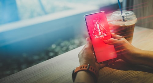 Person holding smartphone with a malware warning alert on the screen