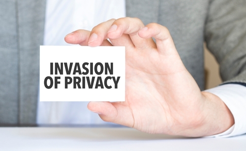 Person holding a card with the words "Invasion of Privacy" written in bold