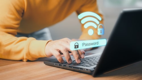 Person using a laptop with a floating password input and secure Wi-Fi icon