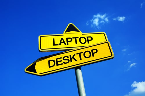 Yellow street signs pointing in opposite directions labeled "Laptop" and "Desktop" against a blue sky