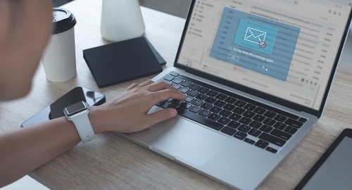 Person using a laptop with an email notification indicating a possible email hack or security breach