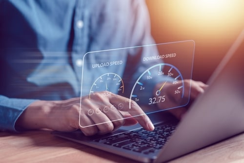 Person using a laptop with digital graphics showing internet upload and download speed test results.