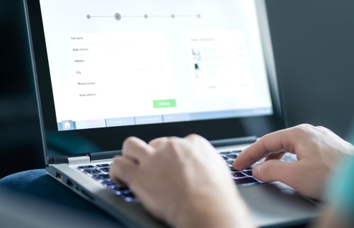 Person filling out an online form with personal information on a laptop