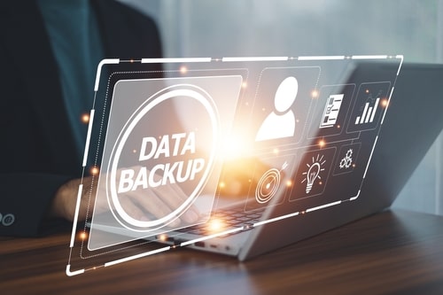 Person using a laptop with virtual interface showing "Data Backup" and digital icons
