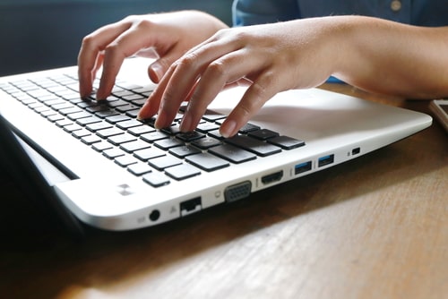 Person typing on laptop keyboard, creating or editing an email signature