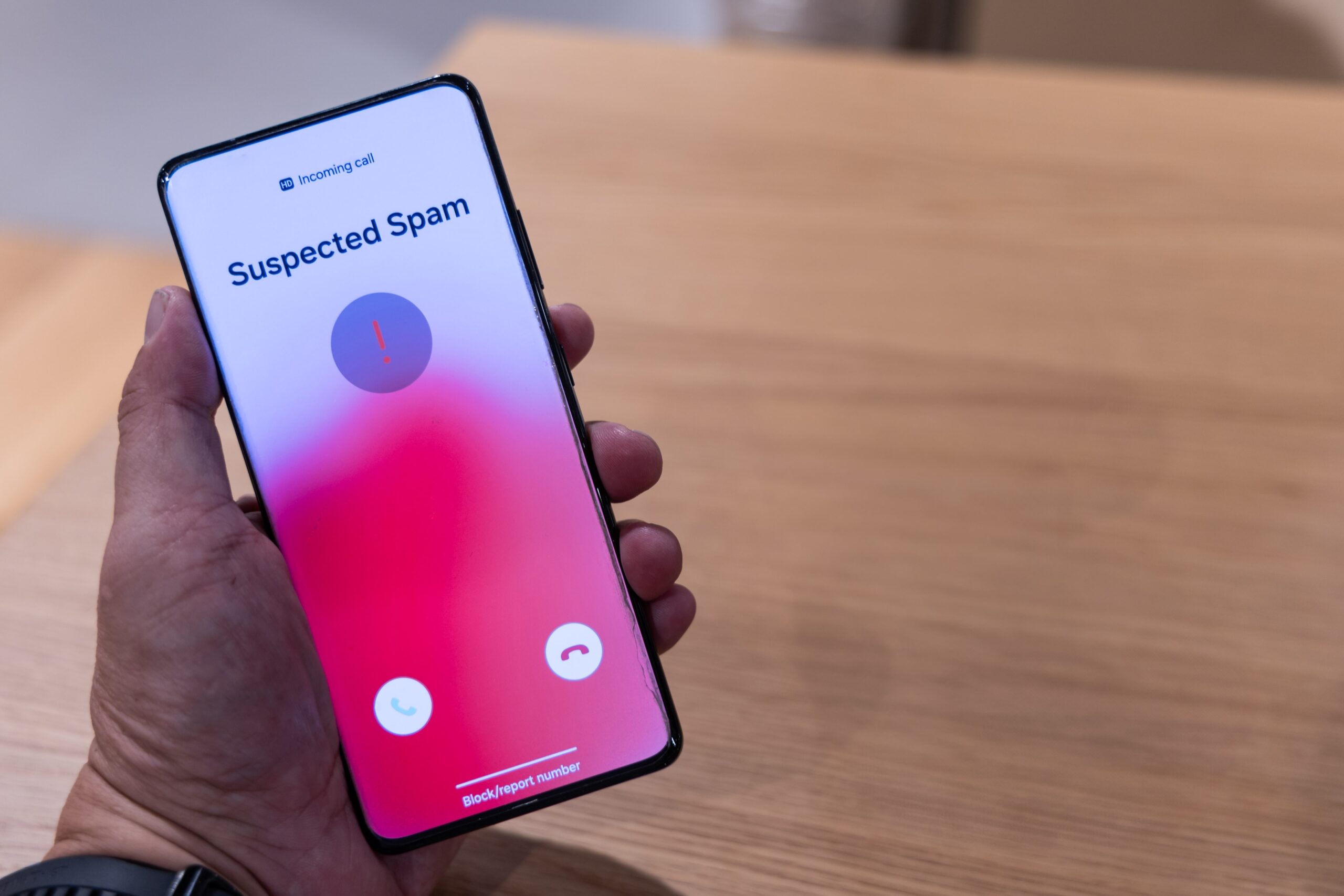 Person holding smartphone showing suspected spam call warning on screen