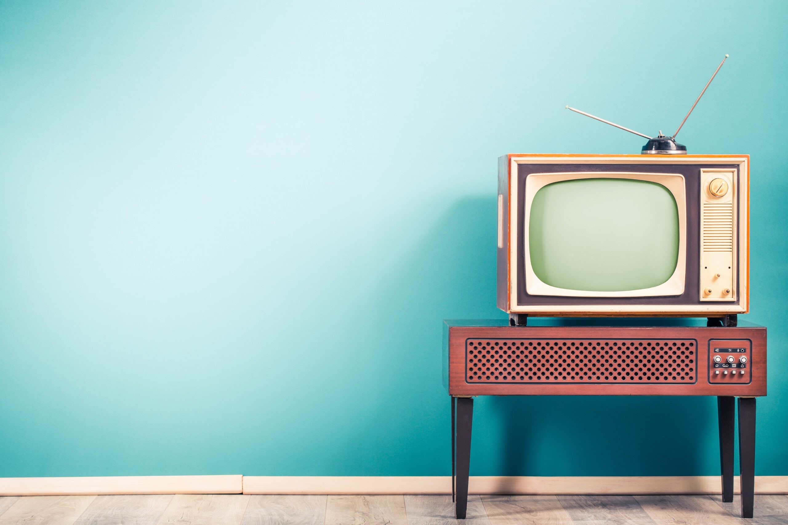 Retro television set on mid-century cabinet against teal wall background