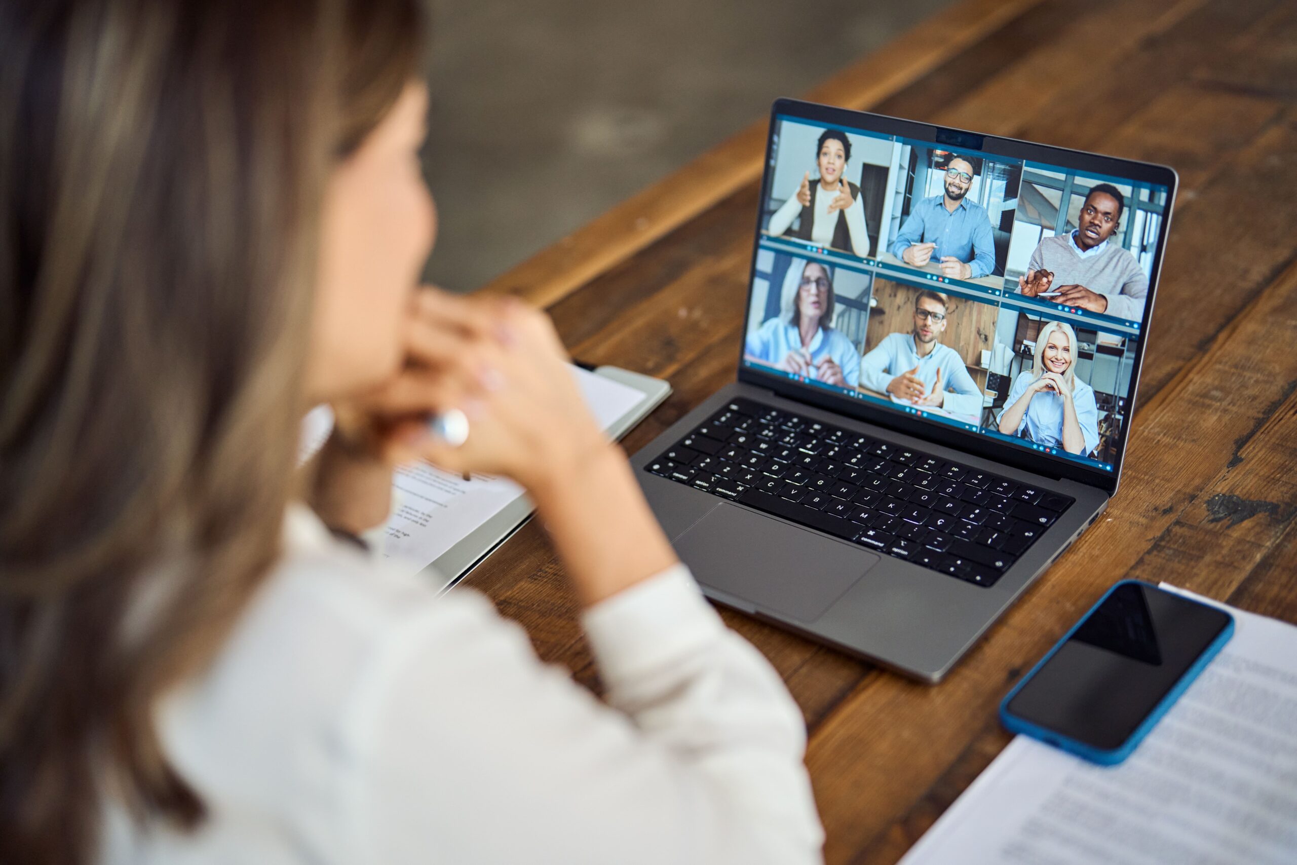 Woman sitting at wooden table on skype call with colleagues