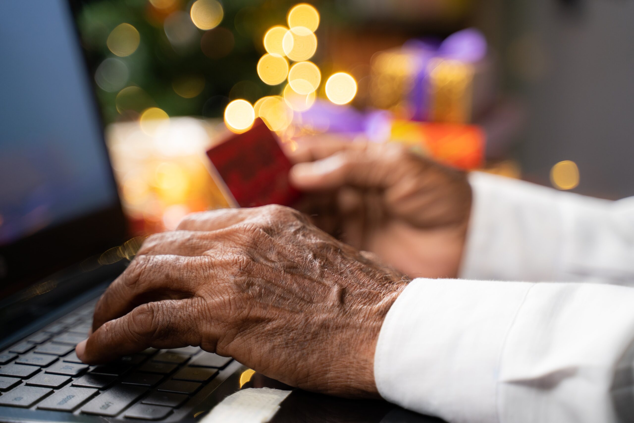 man browsing laptop with credit card in hand with christmas tree in background