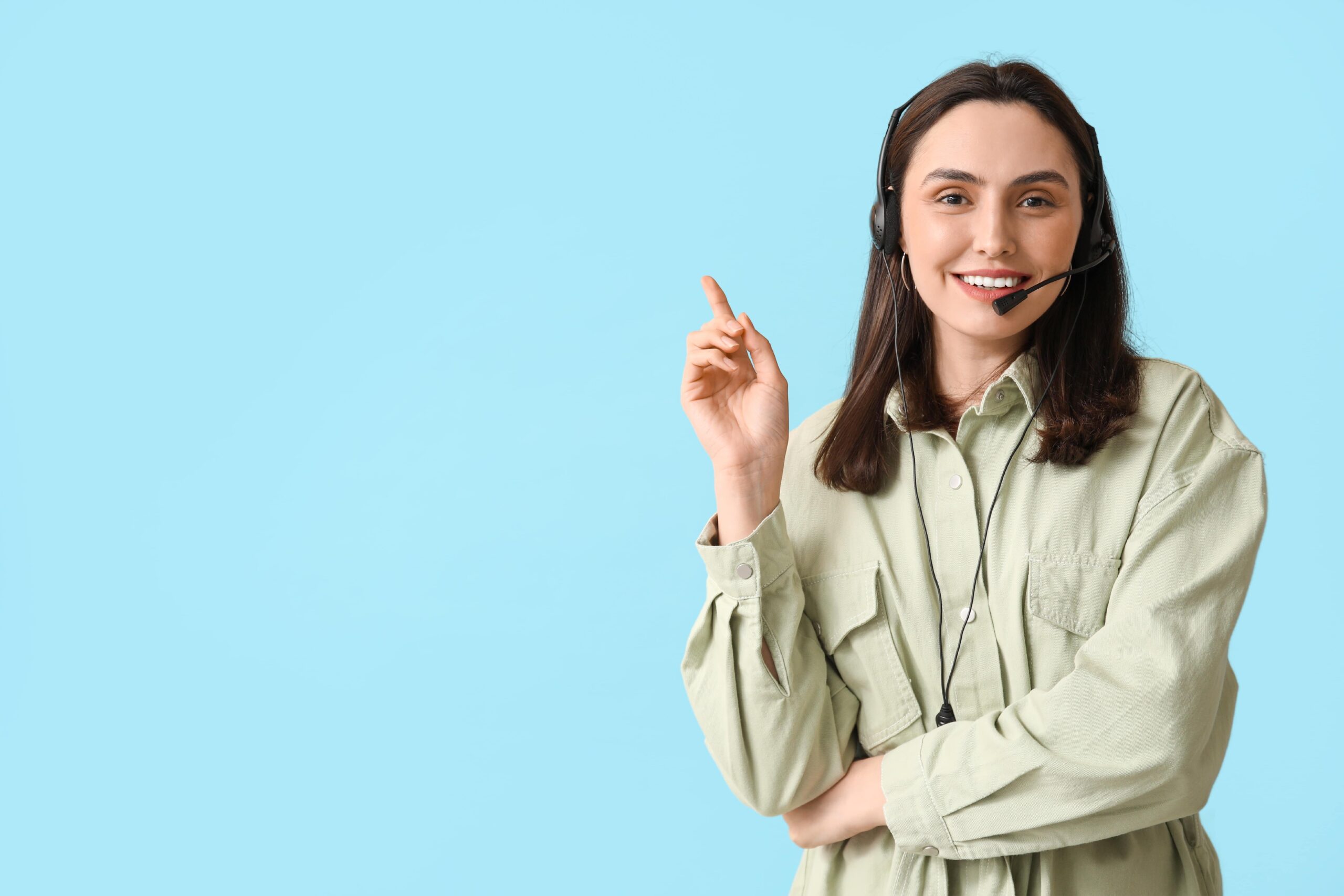 Woman working in tech support holding up her finger wearing a headset