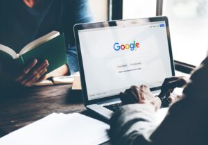 A person working on their laptop that is showing the google search engine home page.