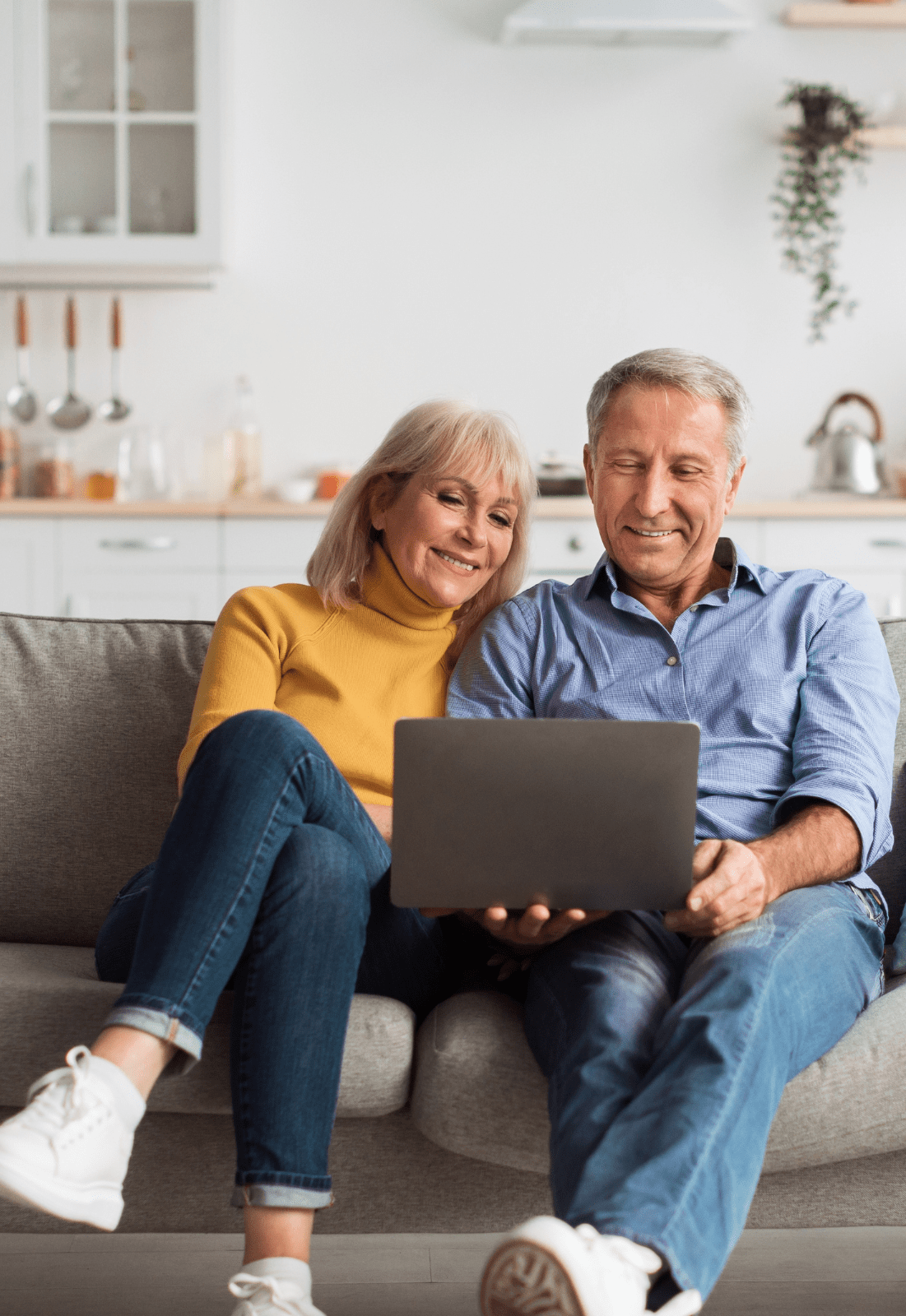 couple sitting on couch using laptop - smiling.