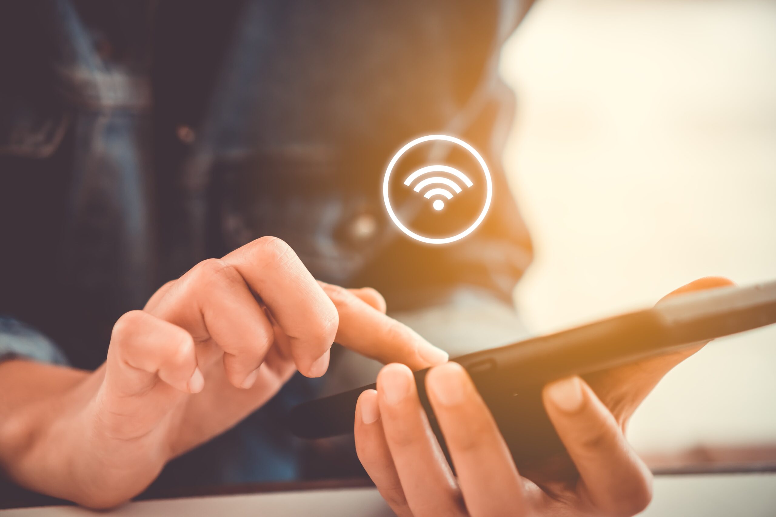 a person on their mobile device with a wifi symbol floating above the device.