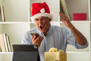 man with santa claus hat in the office shouting and angry with the phone