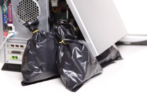 Desktop computer tower surrounded by black trash bags, symbolizing bloatware and slow computer.