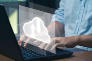 Businessman typing on computer with a virtual cloud over the keyboard