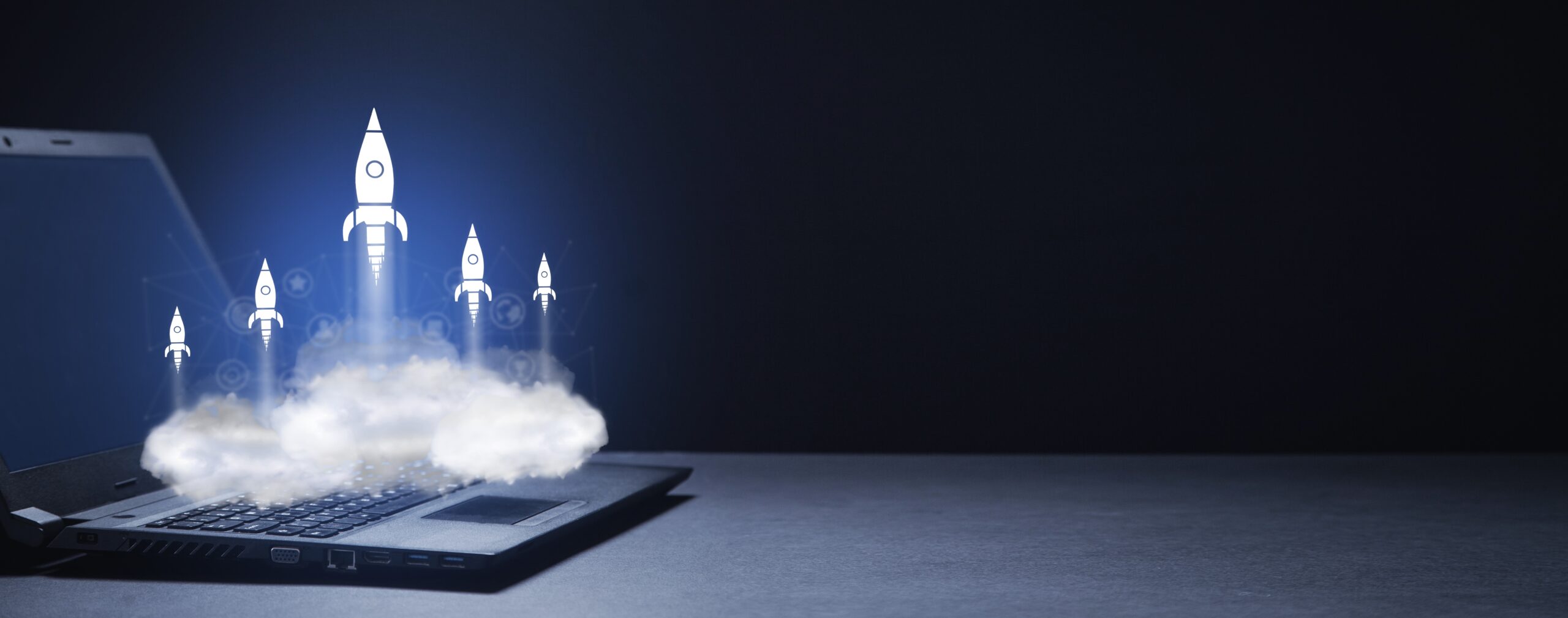 Open laptop on a dark background with illustrated rockets launching upward from the keyboard, representing improved computer speed and performance.