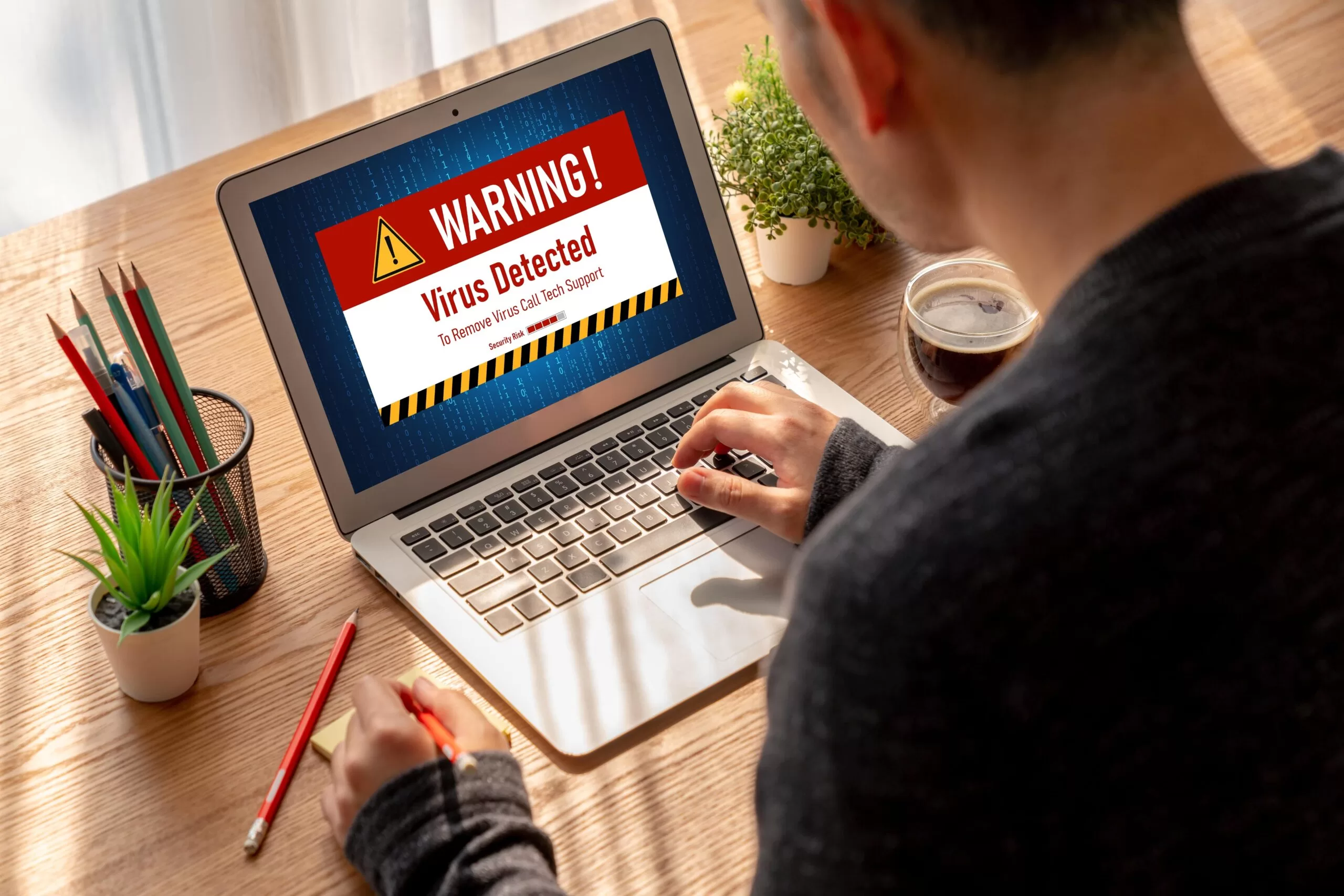 Person viewing virus detected warning on laptop screen, indicating possible malware or scam alert