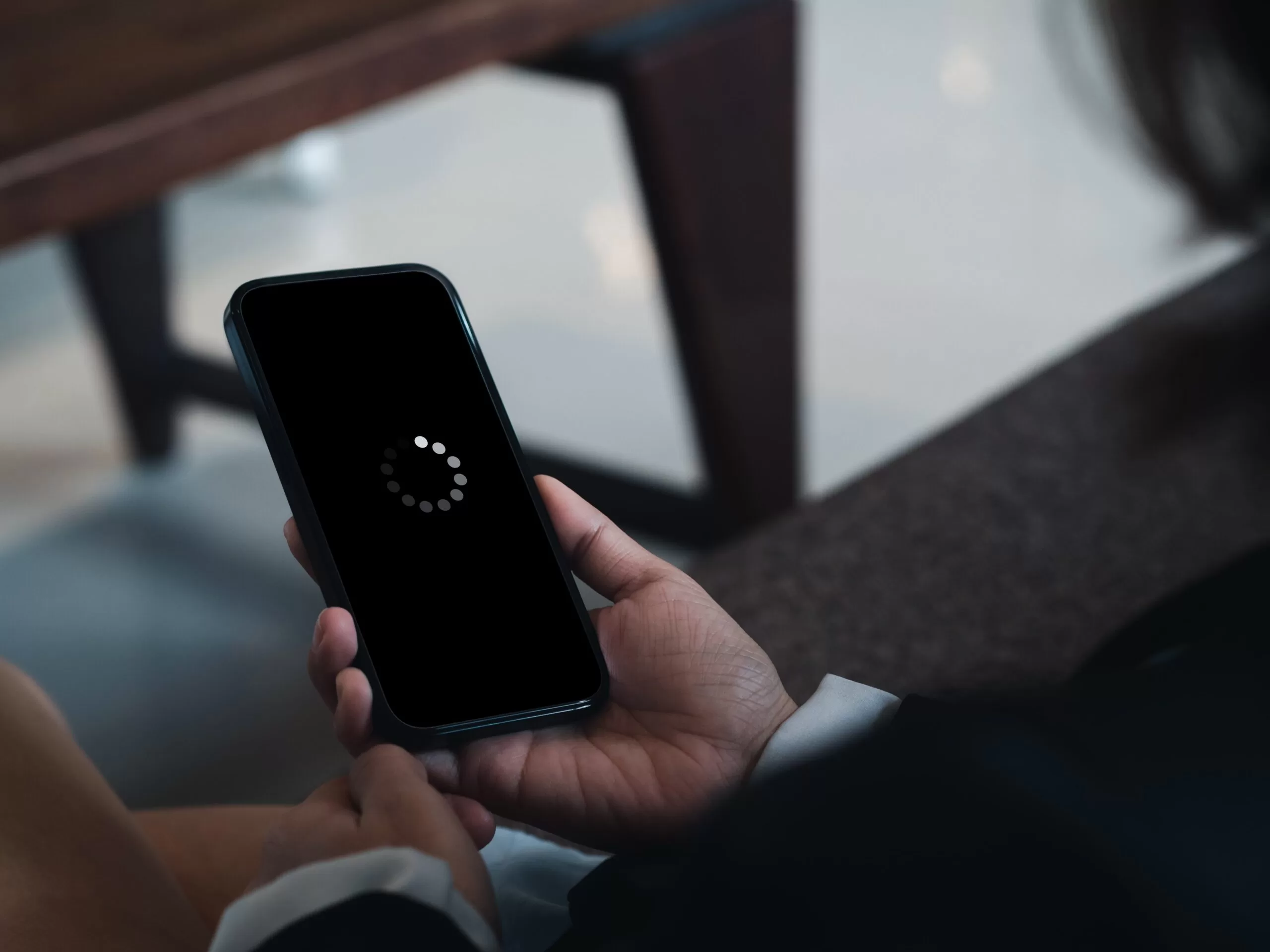 A person holding a mobile device that is displaying a loading symbol.