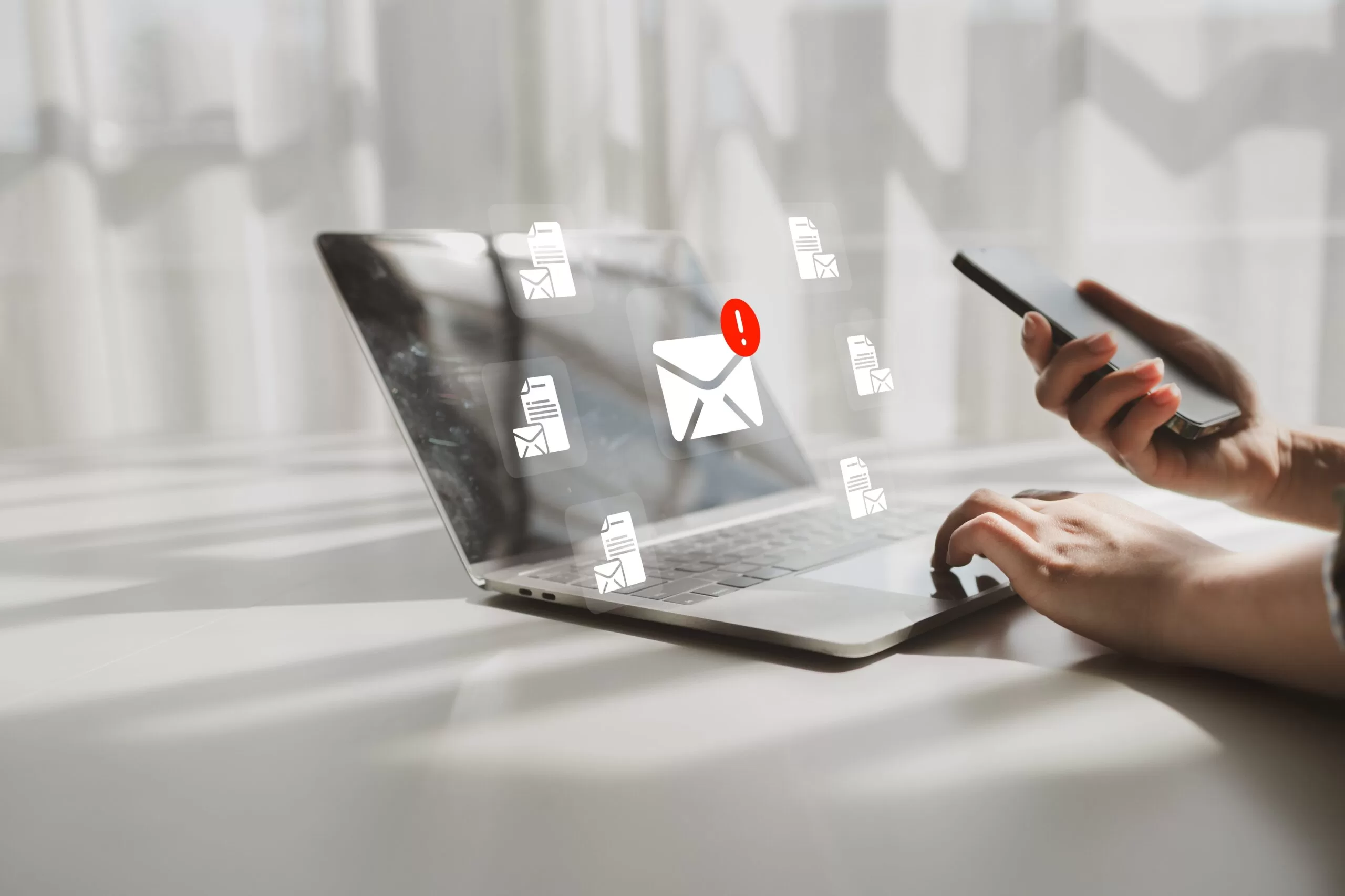 a professional individual working on their laptop that is projecting an email alert surrounded by opened email files.