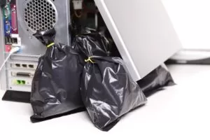 Desktop computer tower surrounded by black trash bags, symbolizing bloatware and slow computer.