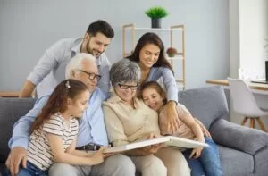 Happy multi-generational family sitting on a couch together, smiling and looking at a photo album