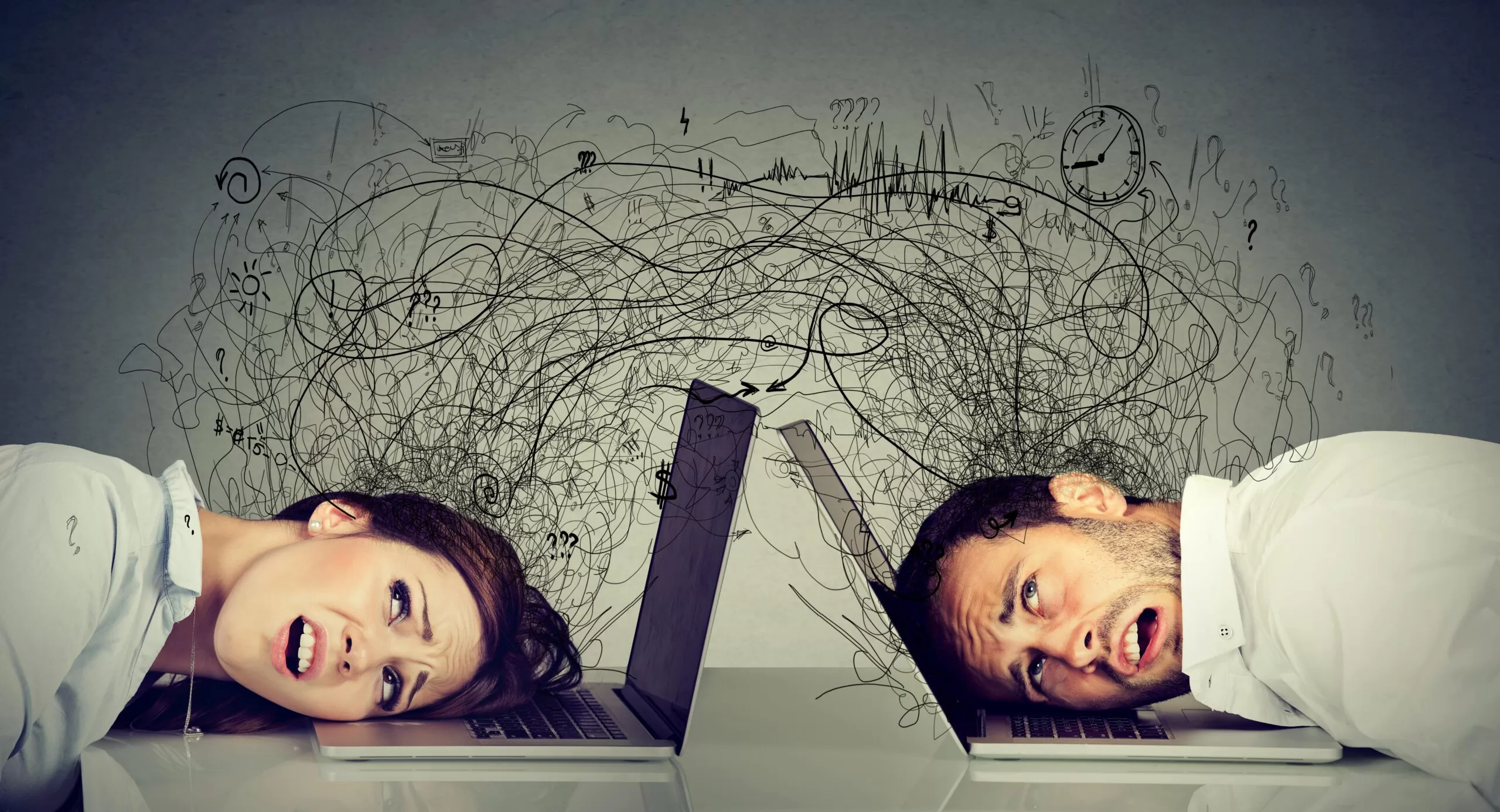 Stressed man and woman with their heads on laptops, surrounded by chaotic scribbles and symbols, representing tech overload or digital burnout.